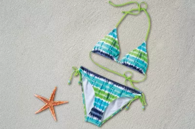 So bitten Sie Ihre Freundin, einen Bikini zu modellieren : Bikini, der auf dem Sand nahe einem Seestern liegt